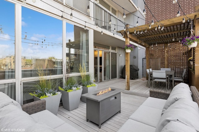 wooden terrace with grilling area, an outdoor living space with a fire pit, outdoor dining space, and a pergola