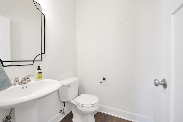 bathroom with toilet, baseboards, a sink, and wood finished floors