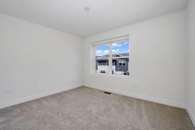 carpeted spare room featuring baseboards and visible vents