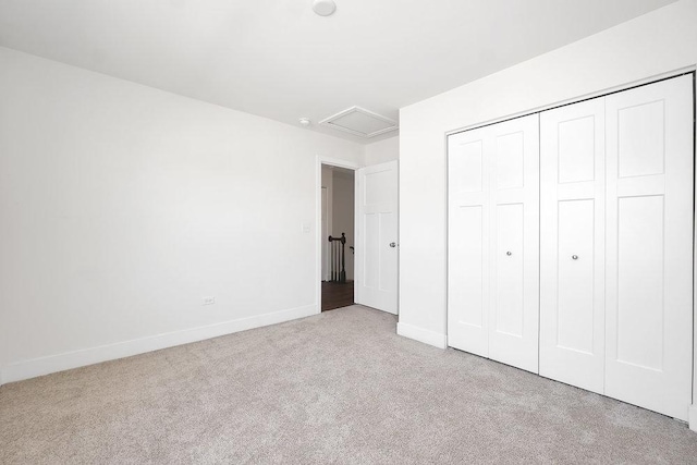 unfurnished bedroom with attic access, baseboards, carpet, and a closet
