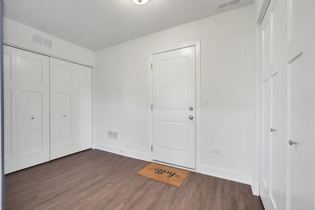 unfurnished bedroom featuring baseboards, dark wood-style floors, and visible vents
