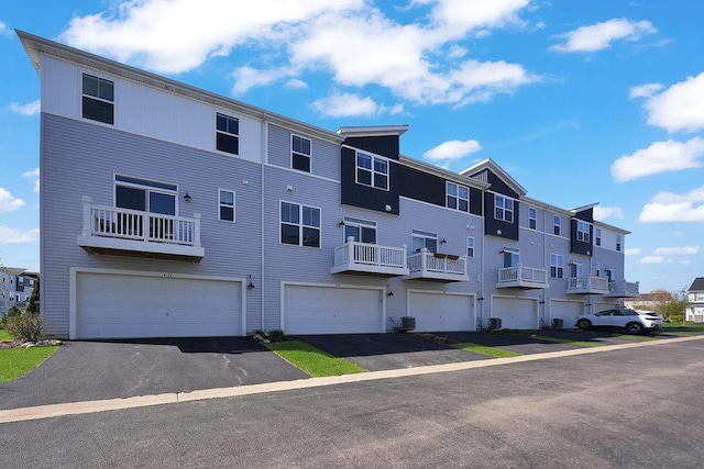 view of property featuring a residential view, an attached garage, and aphalt driveway