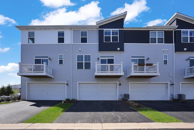 multi unit property with an attached garage, driveway, and cooling unit