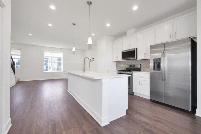 kitchen with backsplash, white cabinets, appliances with stainless steel finishes, and a sink