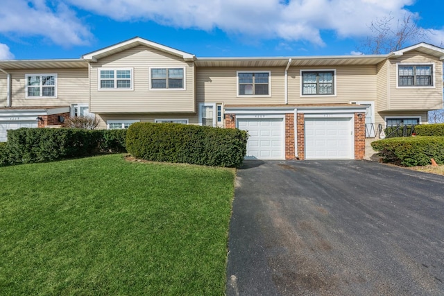 townhome / multi-family property with brick siding, an attached garage, driveway, and a front lawn