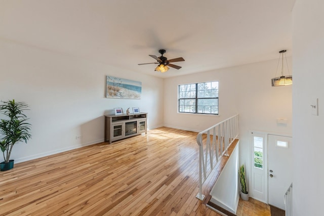 foyer featuring baseboards, ceiling fan, and light wood-type flooring
