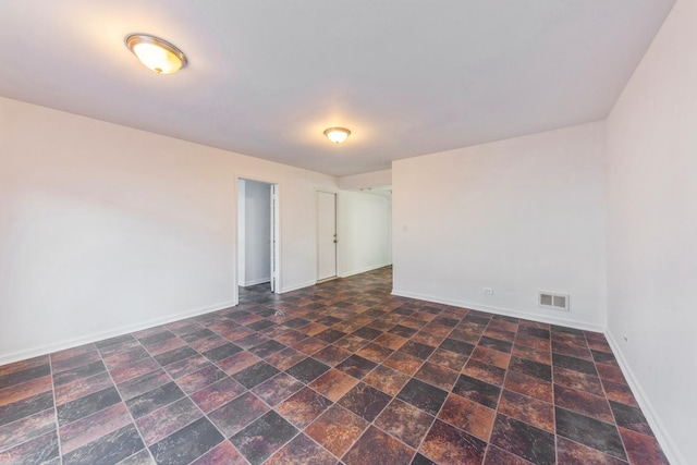 spare room featuring visible vents, baseboards, and stone finish floor