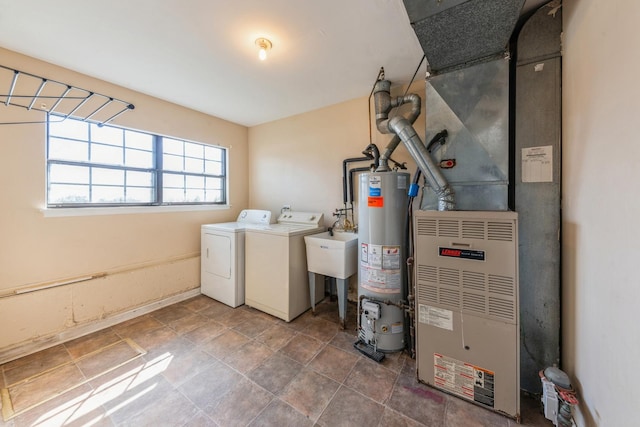 washroom with gas water heater, laundry area, a sink, heating unit, and washer and dryer