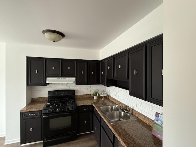 kitchen featuring a sink, dark cabinetry, black range with gas cooktop, tasteful backsplash, and under cabinet range hood
