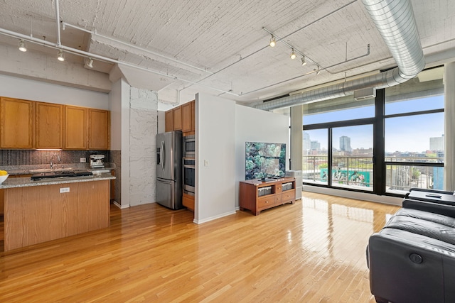 1530 S State St Unit 523, Chicago, IL 60605 - kitchen featuring backsplash, appliances with stainless steel finishes, brown cabinets, track lighting, and light wood finished floors