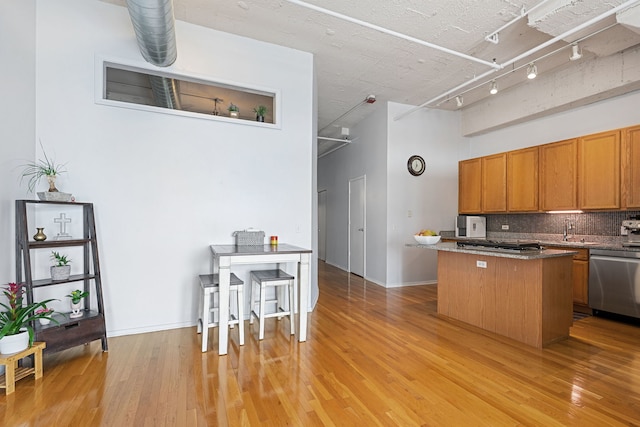 1530 S State St Unit 523, Chicago, IL 60605 - kitchen with decorative backsplash, a center island, brown cabinets, light wood finished floors, and appliances with stainless steel finishes
