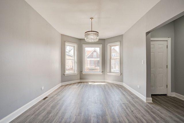 unfurnished dining area featuring baseboards, visible vents, dark wood-style floors, and a chandelier
