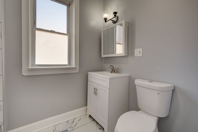 bathroom with toilet, plenty of natural light, marble finish floor, and vanity