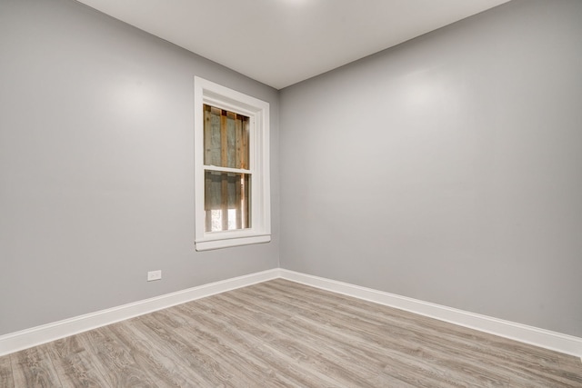 spare room featuring baseboards and light wood-type flooring