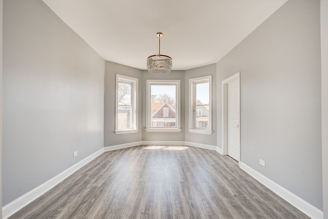 empty room with baseboards, dark wood-style floors, and a chandelier