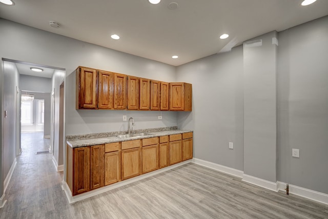 kitchen featuring brown cabinetry, a sink, and light wood finished floors