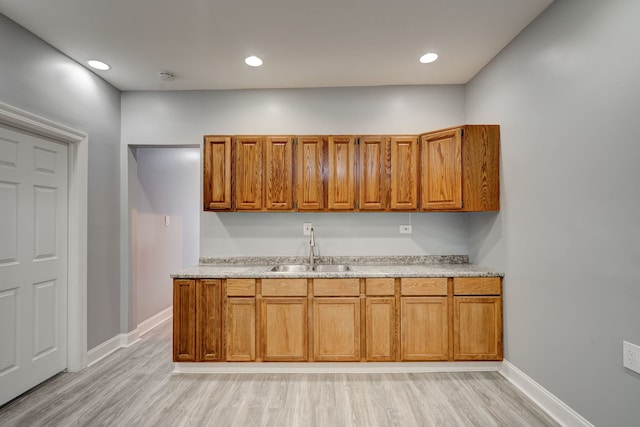 kitchen with brown cabinets, a sink, and light wood finished floors