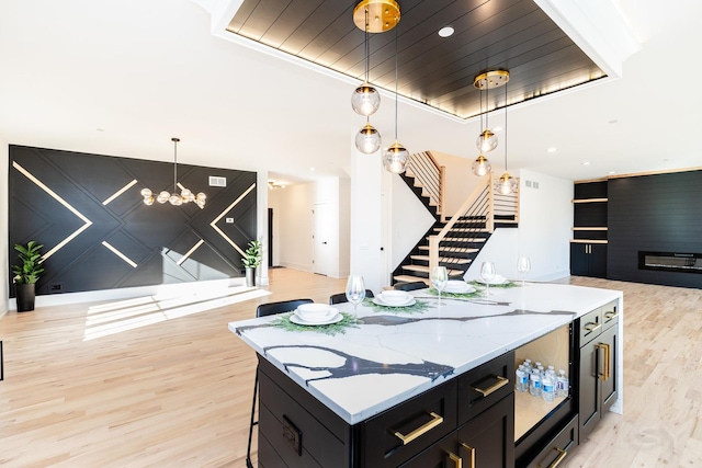 kitchen with dark cabinetry, light wood-style flooring, a center island, open floor plan, and pendant lighting