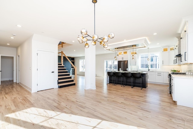 kitchen with recessed lighting, high end appliances, a kitchen breakfast bar, and light wood-style floors
