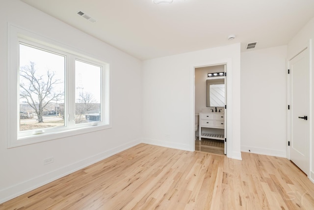 spare room featuring baseboards, visible vents, and light wood-style floors