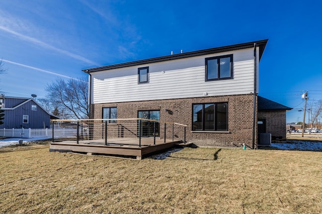 rear view of house featuring fence, brick siding, a deck, cooling unit, and a lawn