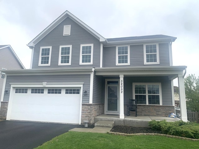 view of front of house featuring covered porch, driveway, and stone siding