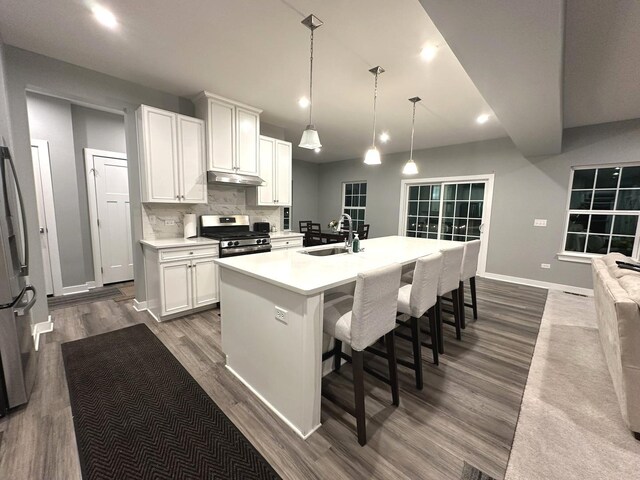 kitchen with appliances with stainless steel finishes, dark wood finished floors, a sink, baseboards, and light countertops
