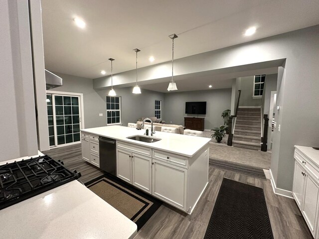 kitchen featuring a sink, light countertops, dark wood-style floors, black dishwasher, and an island with sink