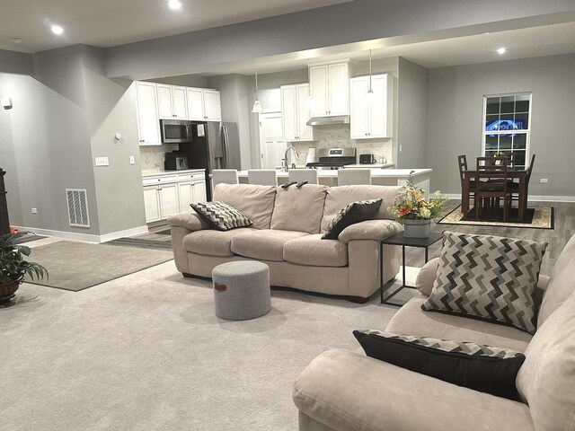 living room featuring baseboards, light carpet, recessed lighting, and visible vents