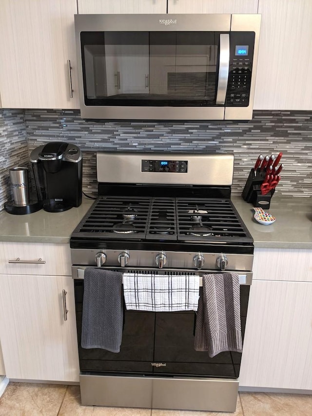 10455 S Forest Ave, Chicago, IL 60628 - kitchen featuring light tile patterned flooring, light countertops, stainless steel appliances, decorative backsplash, and modern cabinets