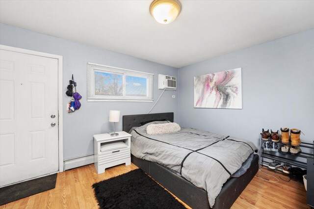 165 Dover Dr Unit 3, Des Plaines, IL 60018 - bedroom with a baseboard heating unit, a wall unit AC, and light wood finished floors