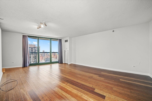 unfurnished room featuring baseboards, floor to ceiling windows, hardwood / wood-style flooring, and a textured ceiling