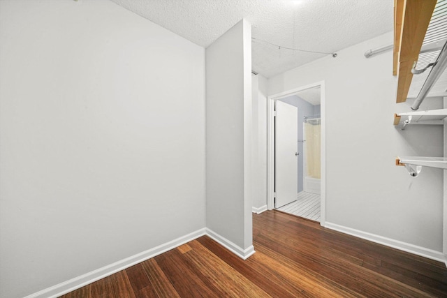 spare room with a textured ceiling, dark wood finished floors, and baseboards