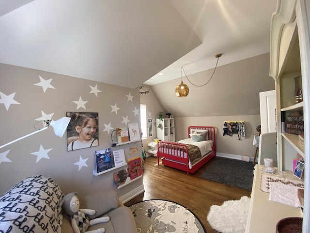 bedroom featuring baseboards, wallpapered walls, vaulted ceiling, and wood finished floors