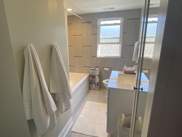 full bathroom featuring visible vents, vanity, wood finished floors, shower / bathtub combination, and toilet