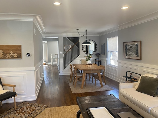 dining area featuring stairway, crown molding, a decorative wall, and dark wood-type flooring