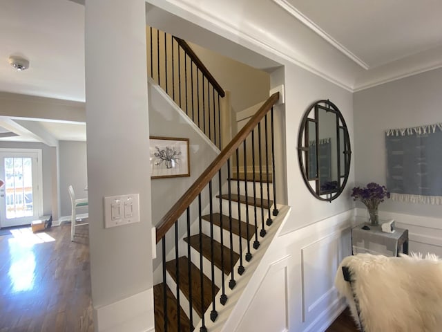 stairway with crown molding and wood finished floors