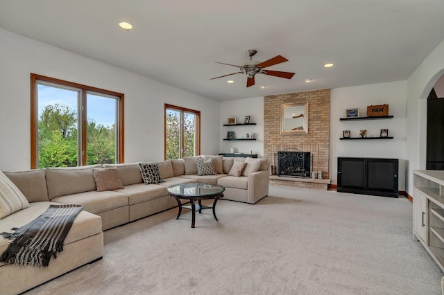living room featuring arched walkways, a ceiling fan, recessed lighting, and a brick fireplace