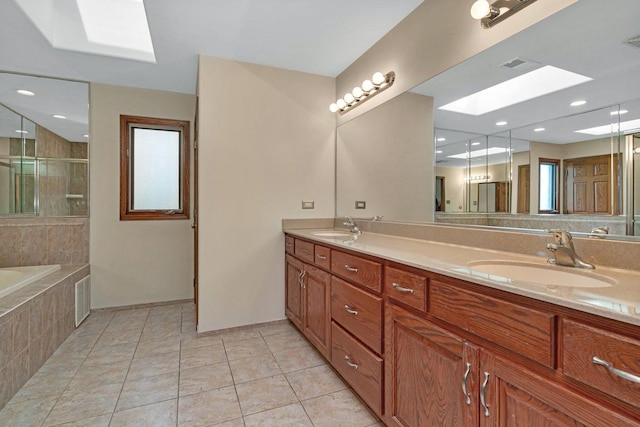 bathroom featuring double vanity, a skylight, tile patterned flooring, a stall shower, and a sink