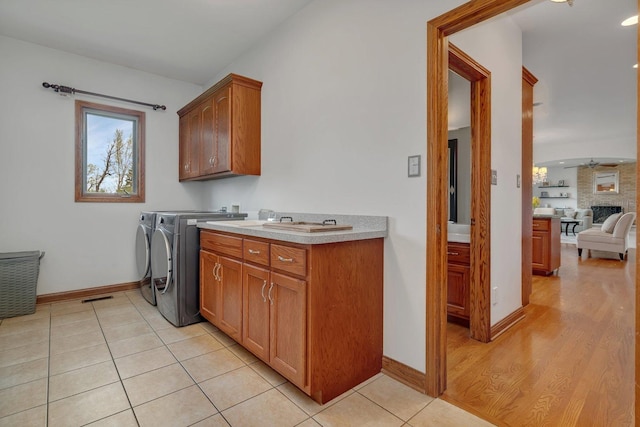 washroom with cabinet space, light tile patterned flooring, ceiling fan, baseboards, and washer and clothes dryer