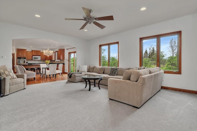 living area featuring recessed lighting, arched walkways, baseboards, and ceiling fan with notable chandelier