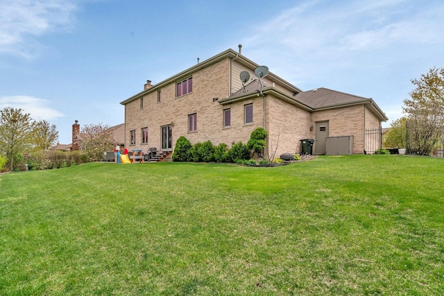 back of property featuring a lawn, brick siding, and a chimney