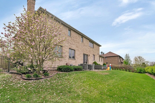 back of house featuring a lawn and a chimney