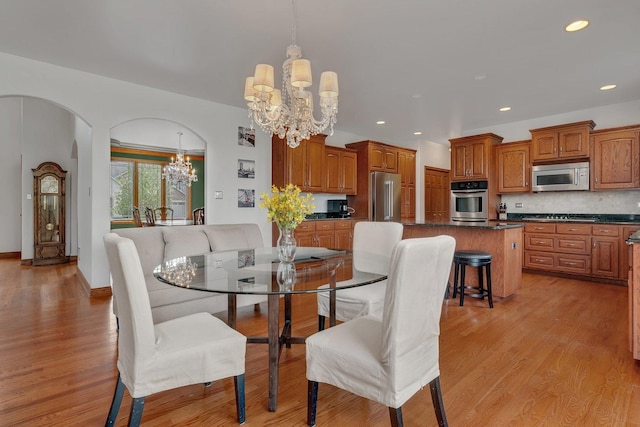 dining room featuring recessed lighting, arched walkways, light wood finished floors, and a chandelier