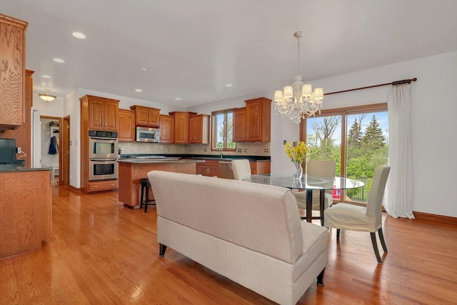 living room with recessed lighting, baseboards, a chandelier, and light wood-style floors