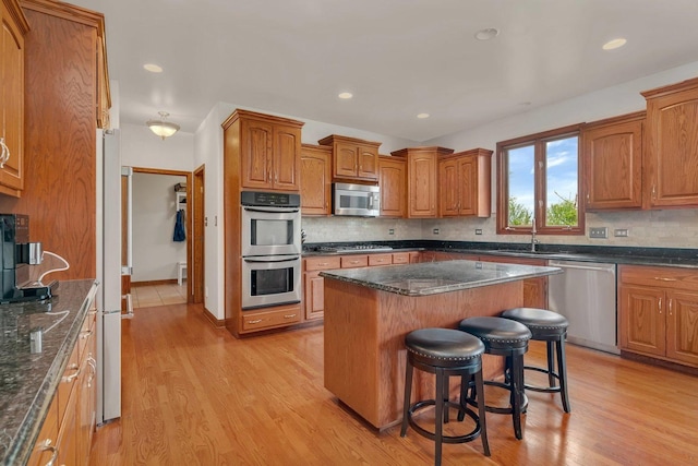 kitchen featuring brown cabinets, appliances with stainless steel finishes, a breakfast bar, and light wood finished floors