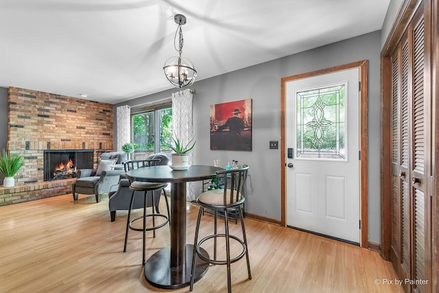 622 Katherine St, Saint Charles, IL 60174 - dining area with light wood-type flooring, a brick fireplace, and a chandelier