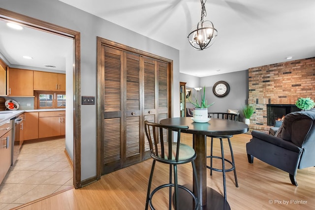 622 Katherine St, Saint Charles, IL 60174 - dining space featuring light wood-style flooring, a fireplace, and a chandelier