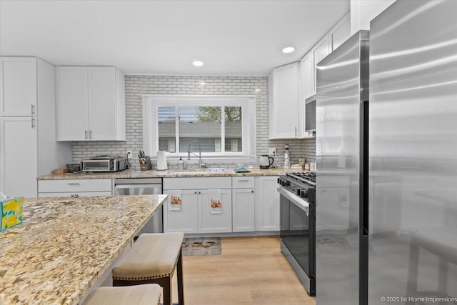 kitchen with white cabinetry, appliances with stainless steel finishes, decorative backsplash, and a sink