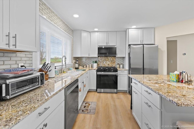 kitchen featuring white cabinets, a sink, light wood finished floors, stainless steel appliances, and a toaster